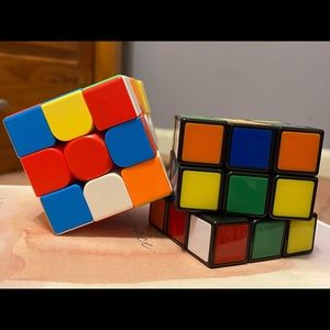 Two rainbow colorful 3 x 3 rubrics cubes